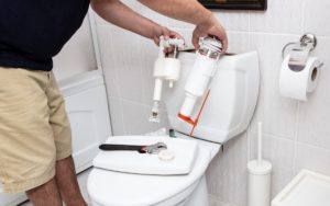 Man using tools repairing reservoir in a bathroom